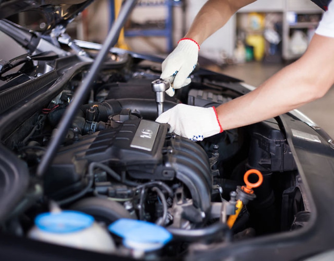 A mechanic working on an engine bay at AliOns Garage