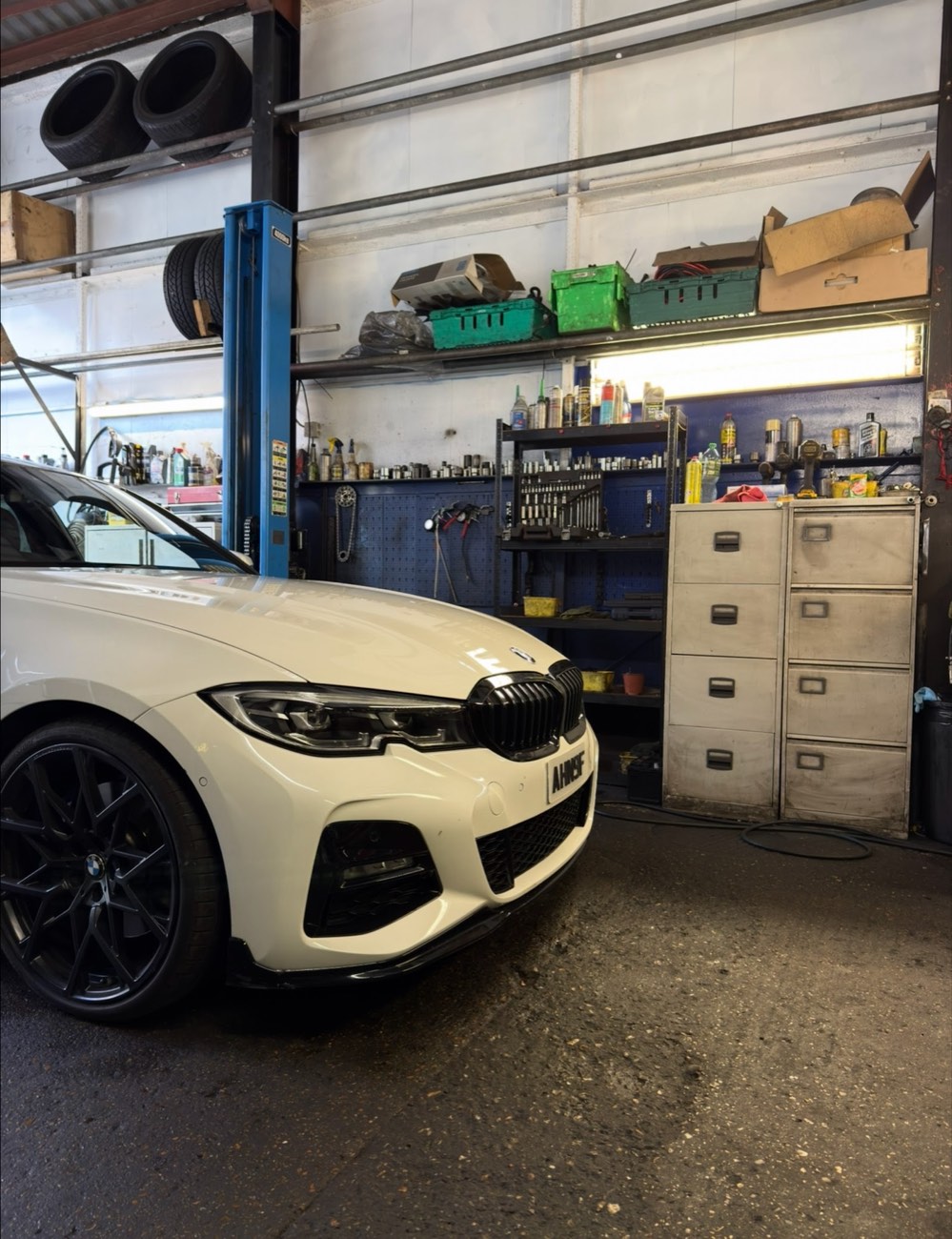 Inside the AliOns Garage workshop on Blount Street, Limehouse, with a car up on the ramp beside the tool bench